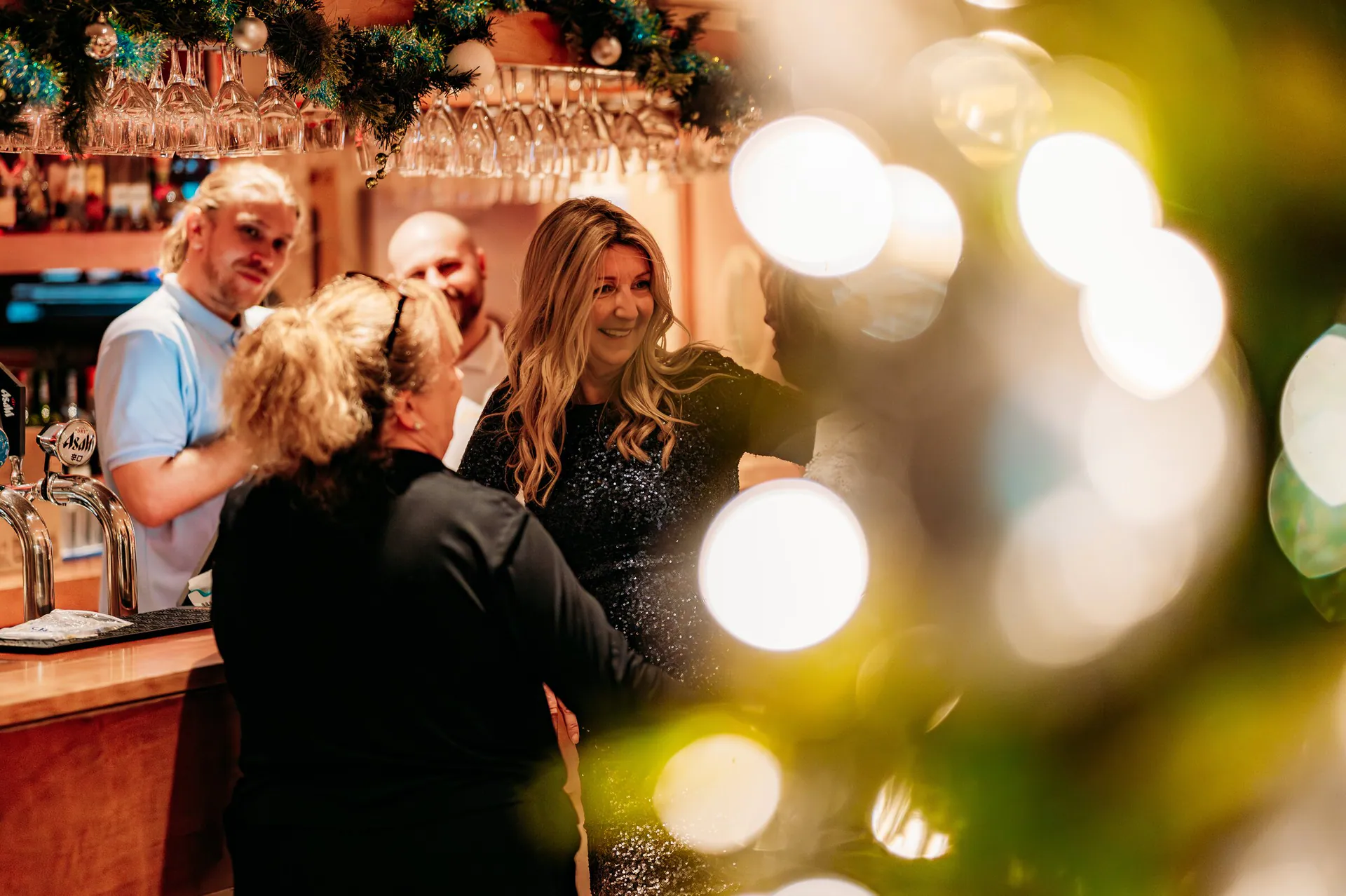Guests celebrating at the bar at Banana Wharf, Christmas lights in the foreground